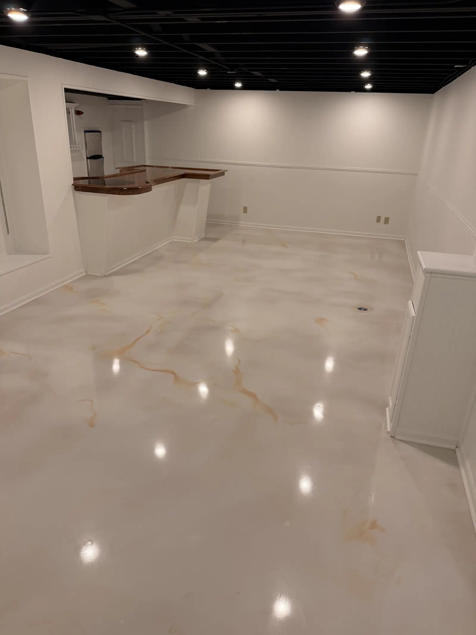 Marble metallic floor reflecting downlights under a live edge timber bar