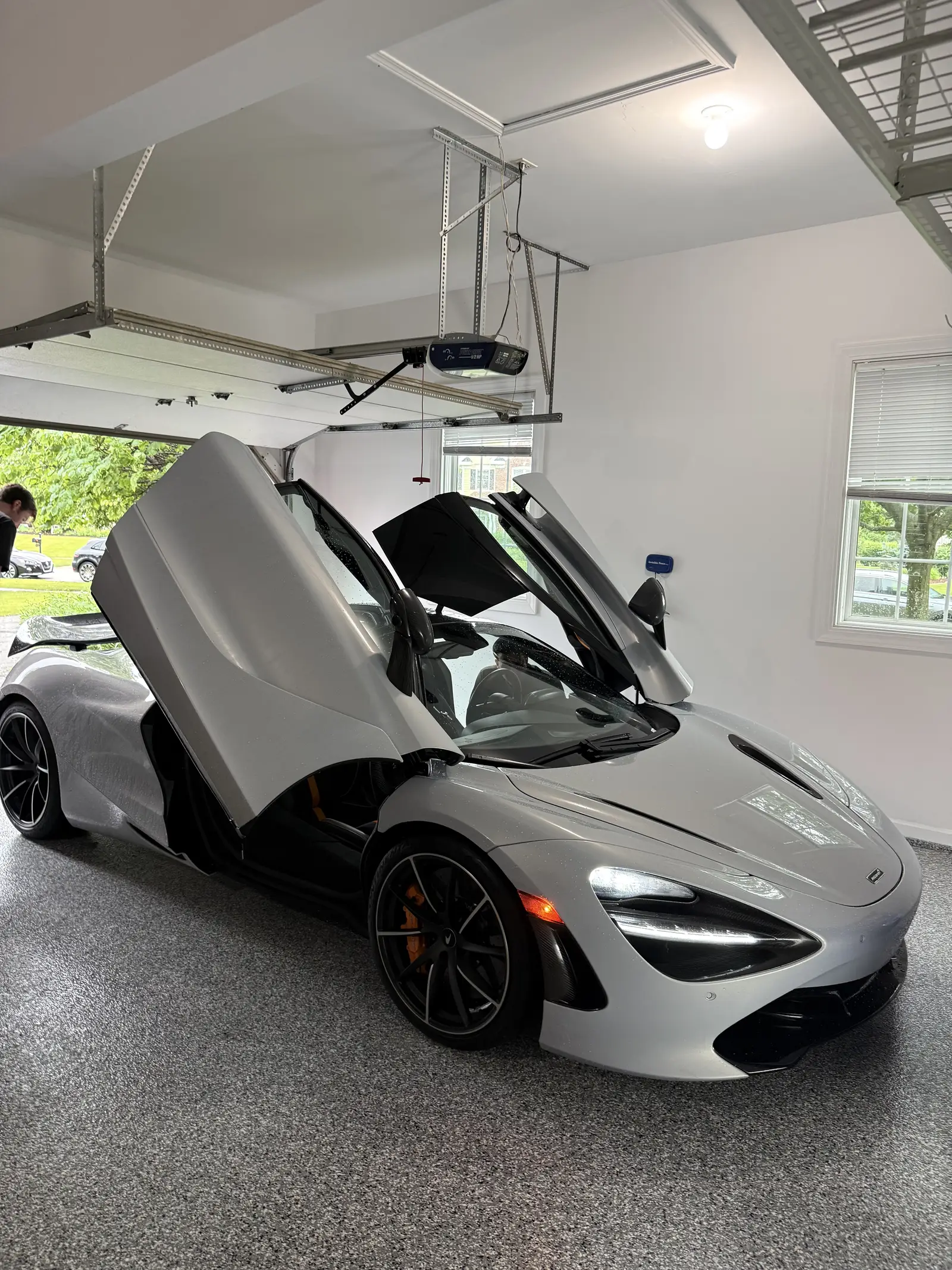 White McLaren with its doors raised on a grey flake coated garage floor